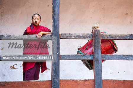 Young buddhistischer Mönch in roten Roben stand neben Red Drum am Wangdue Phodrang Tsechu, Wangdue Phodrang Dzong, Wangdue Phodrang (Wangdi), Bhutan, Asien
