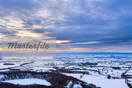 Sinking sun and stormy clouds over a snow covered Gormire Lake from Sutton Bank on the edge of the North Yorkshire Moors, Yorkshire, England, United Kingdom, Europe