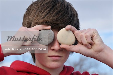 Teenage Boy holding pierres au-dessus des yeux, Sete, France