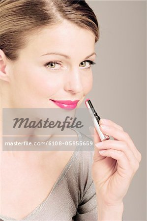 Junge Frau Gesicht Konfektion mit einem Lippenstift, Nahaufnahme (Studio)