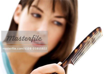 Portrait d'une jeune femme peignant ses cheveux, gros plan (studio)