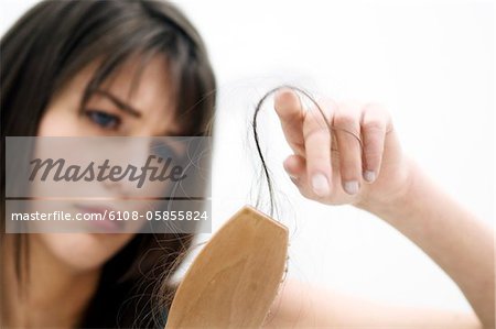 Portrait of a young woman brushing her hair, close up (studio)