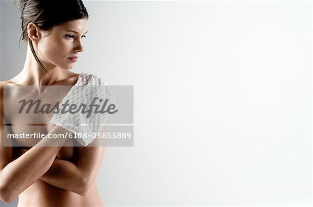 Naked woman with arms on her breasts, using washcloth (studio)