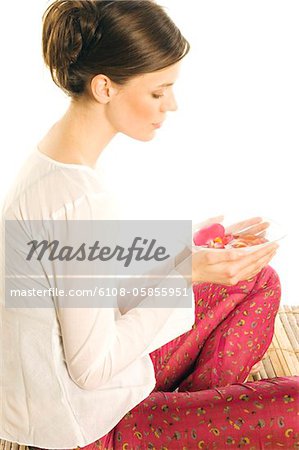 Young woman holding flower petals in a little dish