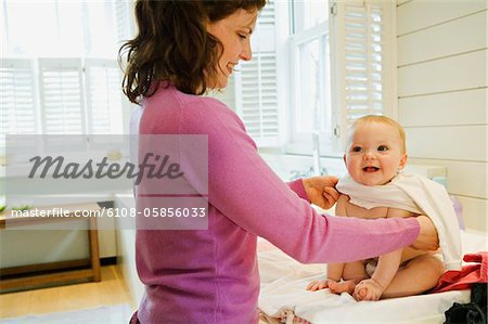 Mother dressing her baby