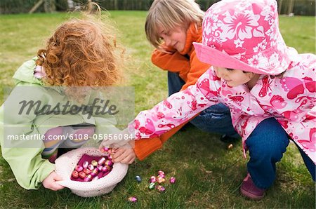 3 children in garden with Easter eggs 3 children in garden with Easter eggs
