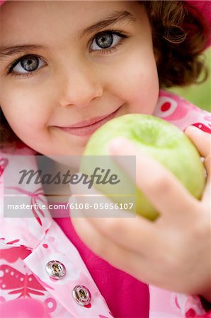 Petite fille tenant une pomme, gros plan