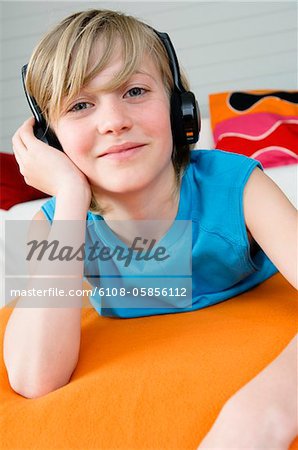 Boy lying on a bed, wearing headphones