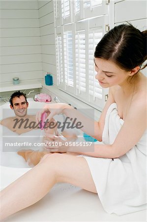 Junge Frau eingewickelt in ein Handtuch, Pediküre erteile Mann im Bad