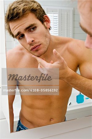 Barechested man in front of bathroom mirror