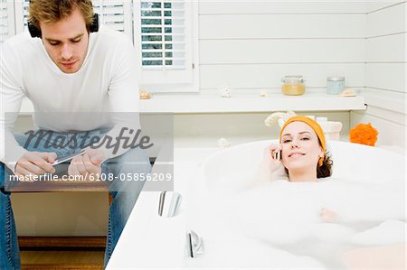Couple dans la salle de bain, femme de téléphoner dans le bain, l'homme avec un casque, le dépôt de sa ongles