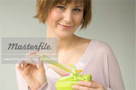 Portrait d'une jeune femme, un cadeau d'ouverture, en regardant la caméra