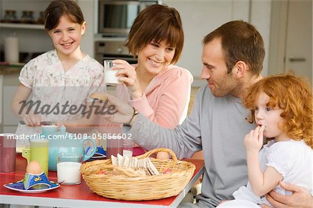 Couple et 2 petites filles prenant son petit déjeuner