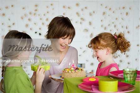 Femme et 2 petites filles avec gâteau d'anniversaire