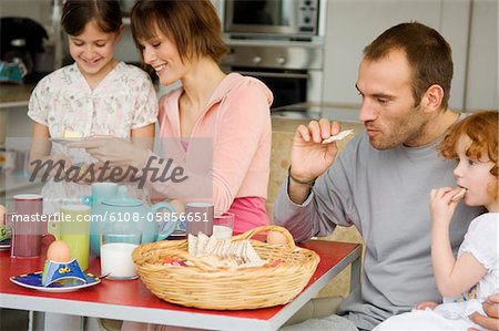 Couple et 2 petites filles à la table du petit déjeuner