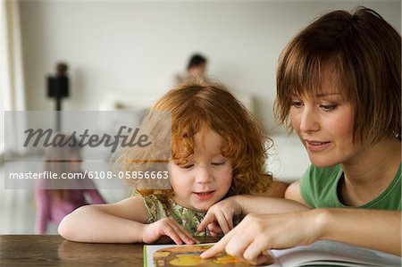 Little girl and woman reading children's book