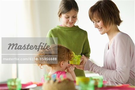 2 kleine Mädchen geben präsentieren lächelnde Frau