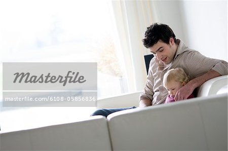 Man and little boy sitting on a sofa in a living-room