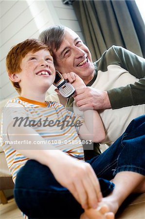 Smiling senior man and boy using a mobile phone