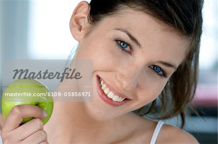 Portrait d'une jeune femme souriante tenant une pomme