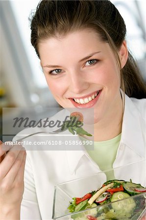 Portrait d'une jeune femme souriante manger salade composée