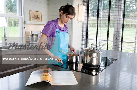 Young woman cooking, recipe book