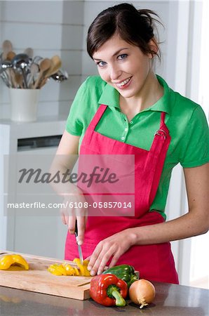 Jeune femme souriante, hacher les légumes
