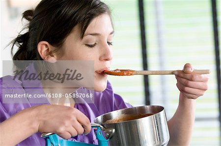 Young woman tasting tomato sauce