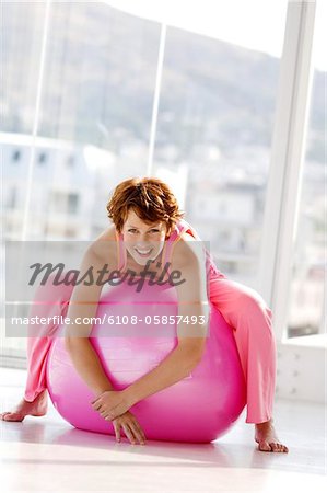 Young smiling woman lying on a big pink balloon