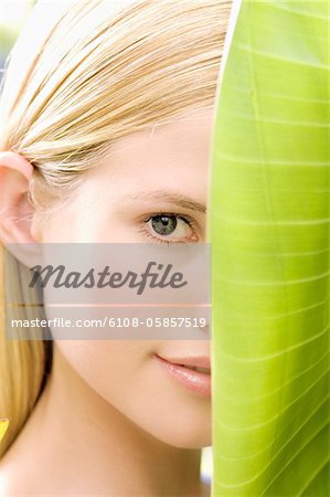 Portrait d'une jeune femme regardant la caméra, feuille de bananier, plein air