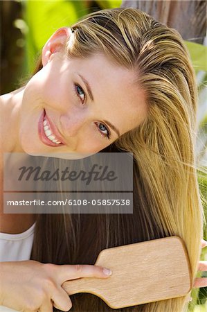 Portrait of a young woman brushing her hair, outdoors