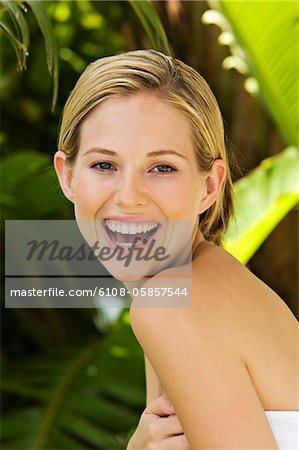 Portrait of a young woman smiling, towel on her body, outdoors