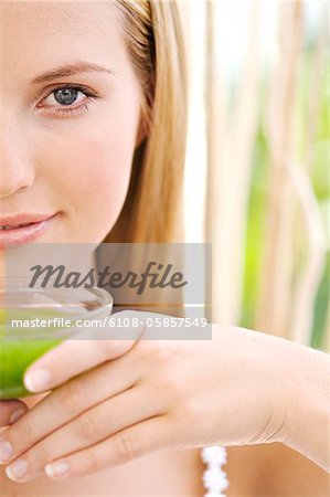 Portrait de la moitié du visage d'une jeune femme, tenant une tasse de thé vert, gros plan, à l'extérieur