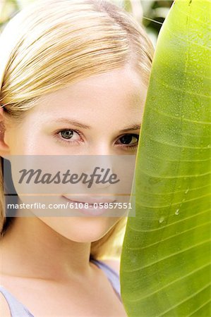 Portrait d'une jeune femme regardant la caméra, feuille de bananier, plein air