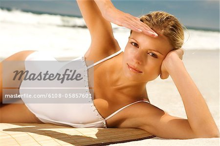 Jeune femme en maillot de bain bronzer sur la plage