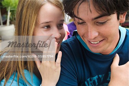 Teenage girl whispering secrets to teenage boy