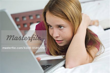 Adolescente allongé sur le lit, à l'aide d'ordinateur portable