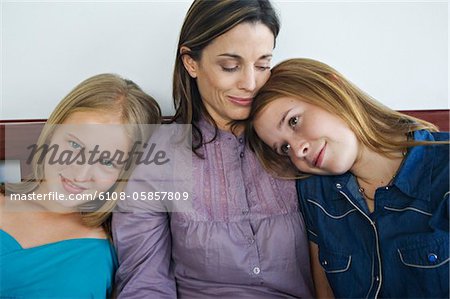 2 teenage girls leaning on woman's shoulders