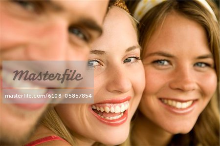 2 junge Frauen und ein Mann für die Kamera Lächeln
