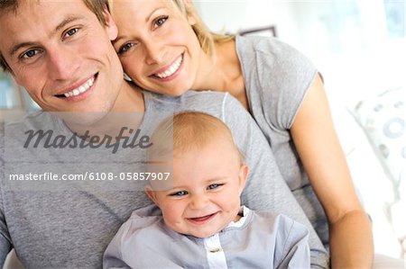 Portrait parents et bébé souriant, à l'intérieur