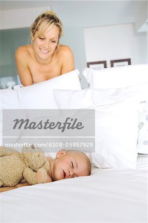 Mother smiling looking at her baby asleep, indoors