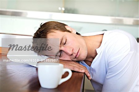 Portrait of a man sleeping on table in kitchen, indoors