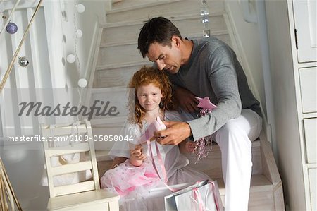 Père et ldaughter ouverture Noël présente, jeune fille tenant un costume de princesse, à l'intérieur