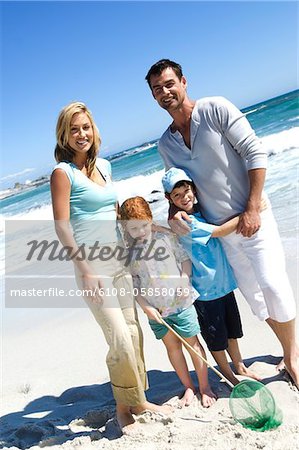 Parents and two children on the beach, posing for the camera, outdoors