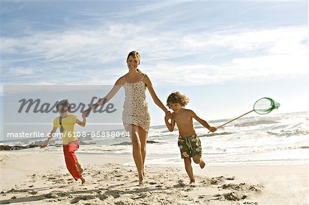 Mother and two children running on the beach, outdoors