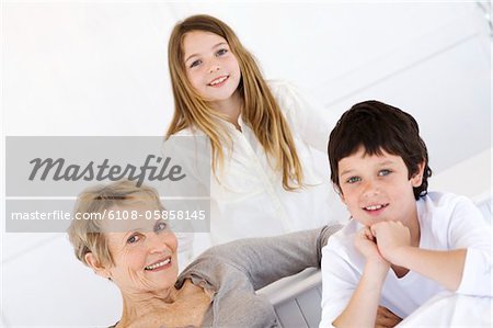 Senior woman and two children smiling for the camera, indoors