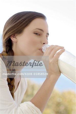 Portrait of a young woman drinking milk from the bottle, outdoors