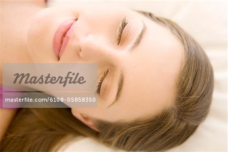 Portrait of a young woman lying, sleeping, indoors