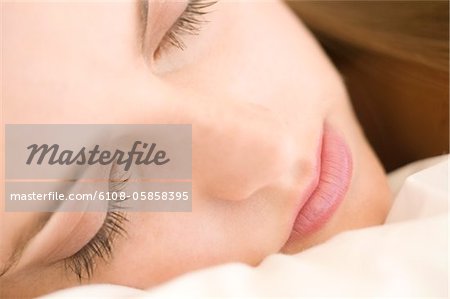 Portrait of a young woman lying, sleeping, indoors