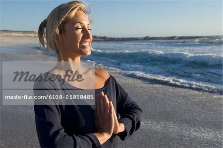 Jeune femme à l'attitude d'yoga sur la plage, en plein air